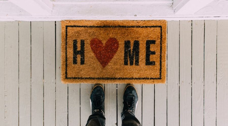 A creative doormat with heart motif symbolizing home at a front porch entrance.